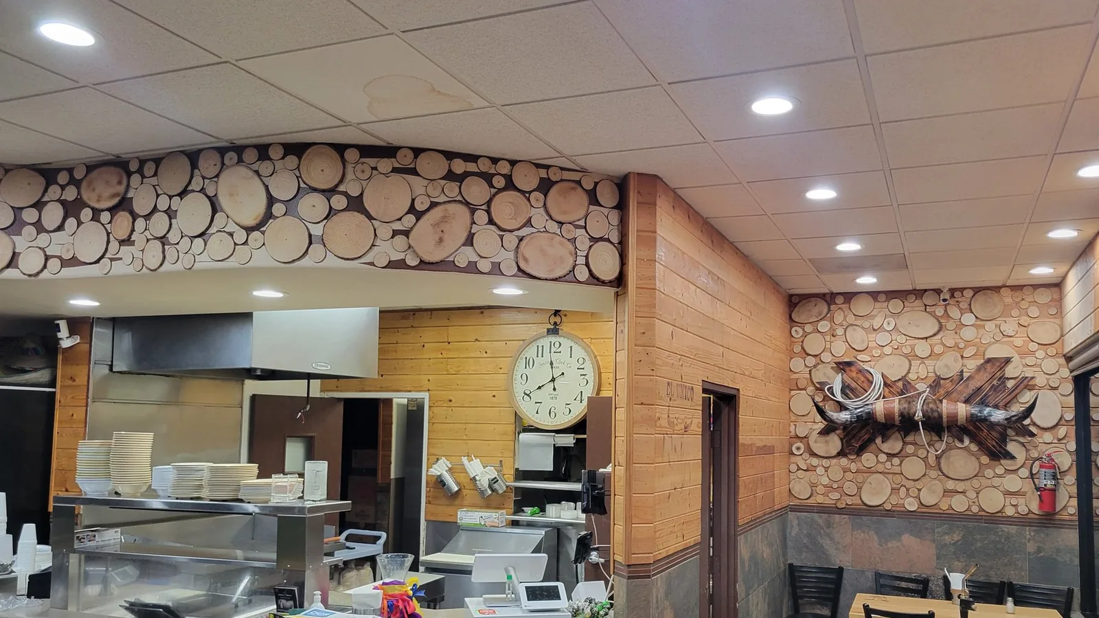 Site photo: a restaurant with pine walls, a wood-slice feature wall and a stainless pass.