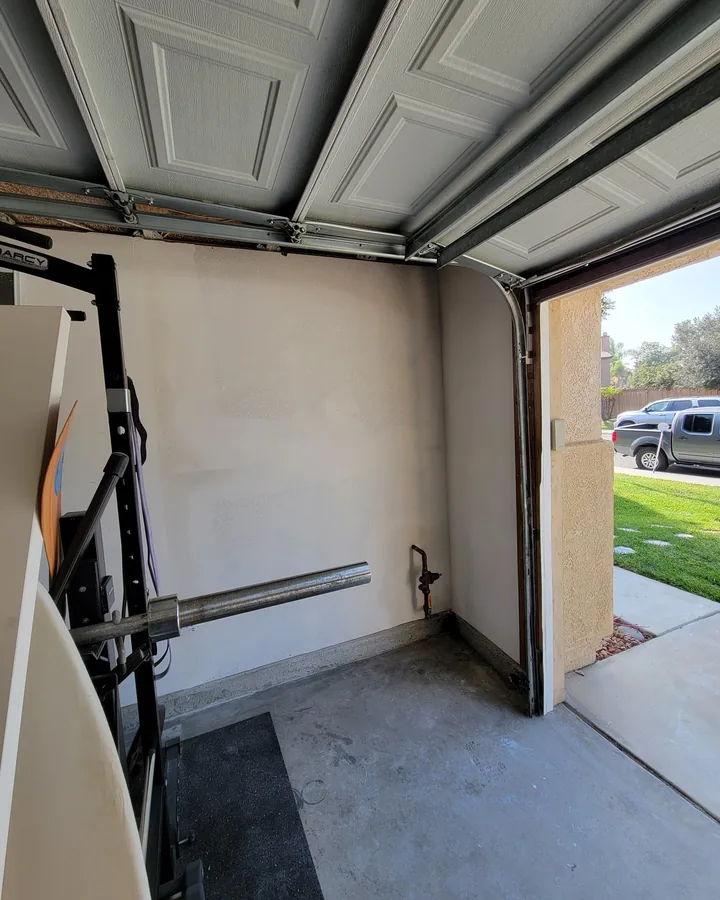 Site photo: the inside of a garage with the door open, a bare wall and a concrete slab.