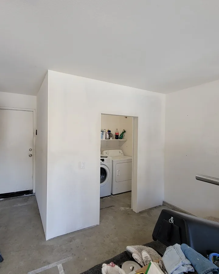 Site photo: new white walls inside a garage, with a closet that holds a washer and dryer.