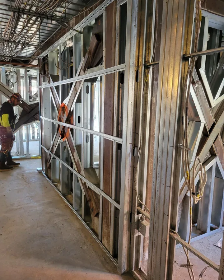 Site photo: interior metal stud walls with diagonal bracing and a worker.