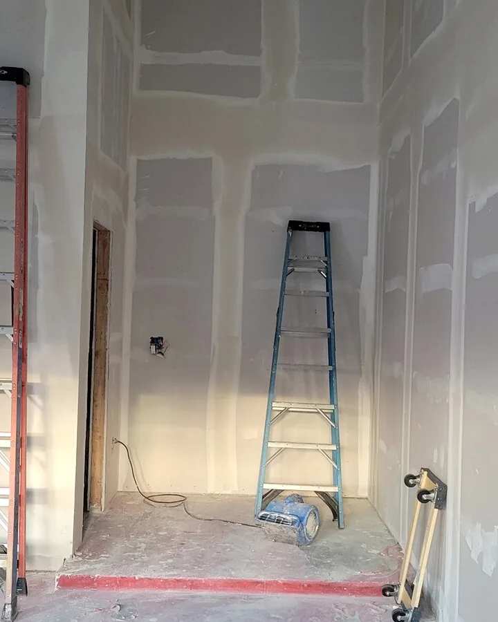 Site photo: drywall with taped joints and a ladder standing in the room.