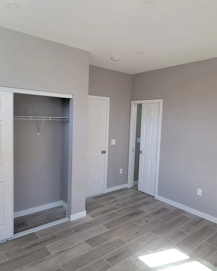 Site photo: a finished bedroom with an open closet, white doors and wood-look floors.